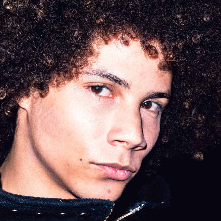 Close direct-flash portrait of a model with curly hair